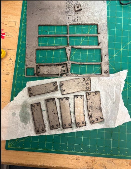 Plasma-cut titanium side armour supports on a cutting mat